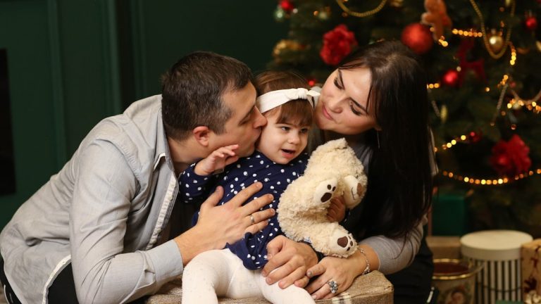 a man and a woman holding a baby and a teddy bear