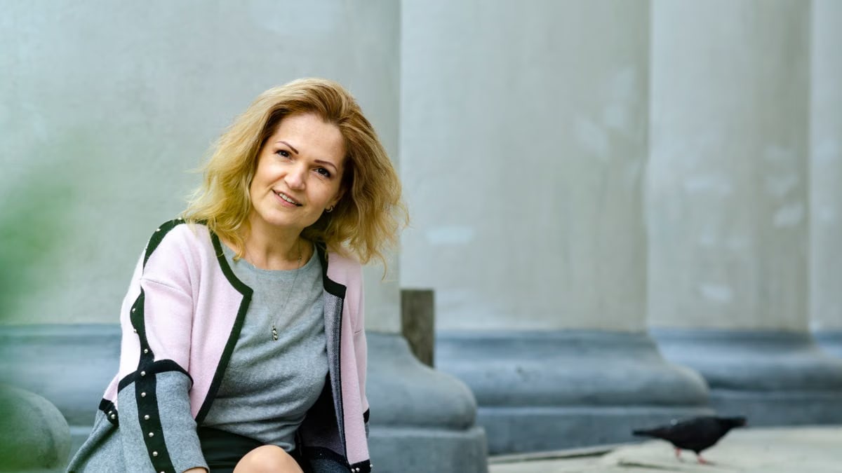 Woman sitting outdoors by classical columns in Lviv, Ukraine. Relaxed and elegant.